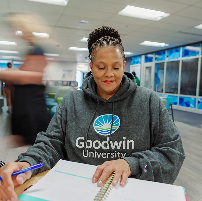 Student wearing a Goodwin University sweatshirt studying at a table