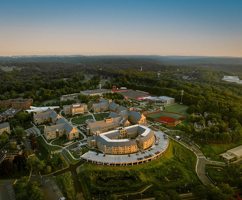 Aerial view of a university campus with academic buildings, athletic fields, and surrounding trees