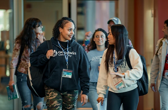 Students walking together in a campus hallway, wearing Goodwin University apparel and badges